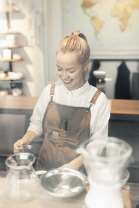 Smiling female barista preparing coffee at counter
