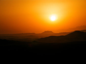 Scenic view of silhouette mountains against romantic sky at sunset