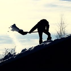 Silhouette man with arms outstretched against sky