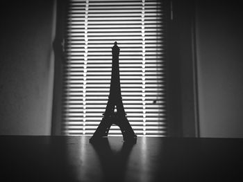 Close-up of eiffel tower souvenir on table against window blinds