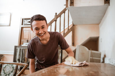 Smiling boy cleaning table at home