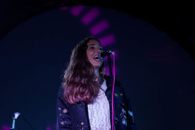 Low angle view of woman singing during concert