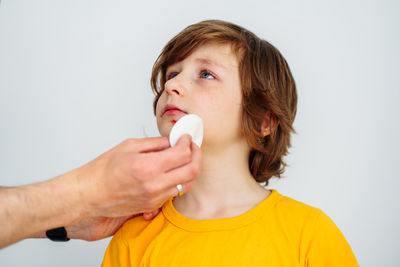  doctor treats bruised wound on boy kid face. cleans addresses the sore wound on child  on white