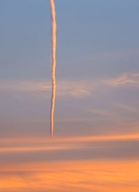Low angle view of vapor trail against sky during sunset