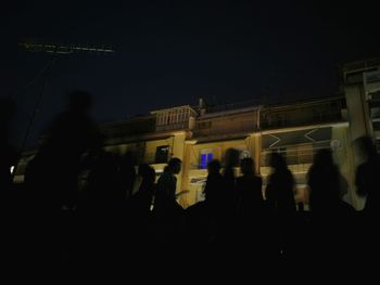 Silhouette people standing in front of building at night
