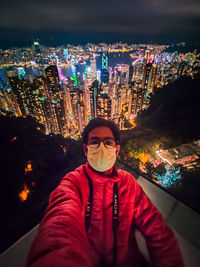 Portrait of man and illuminated buildings in city at night