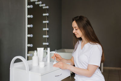 Side view of young woman using mobile phone at home