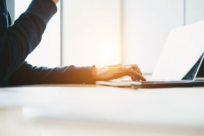 Midsection of person using laptop on table