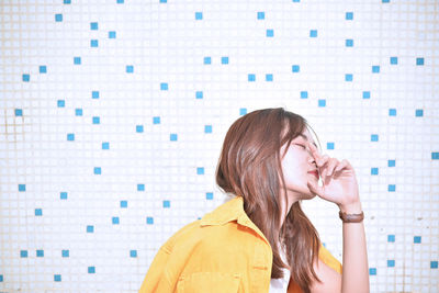 Portrait of woman standing against wall