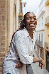 Cheerful woman leaning on railing in balcony