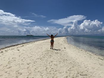 Rear view of woman walking on beach against sky