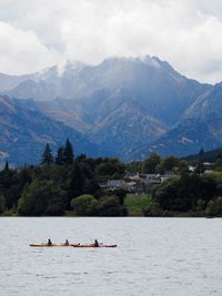People in boat on lake against mountains