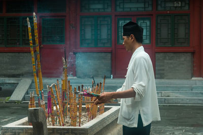 Side view of man standing against building