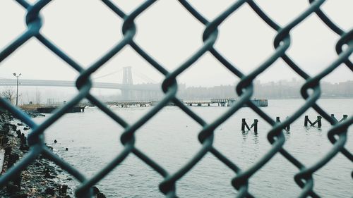 Williamsburg bridge and manhattan bridge from behind a fence on brooklyn shore