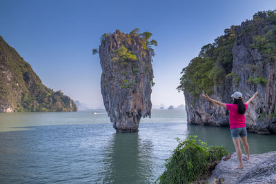 Rear view of woman standing by sea on rock