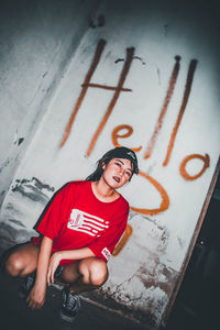 Portrait of young woman standing against wall