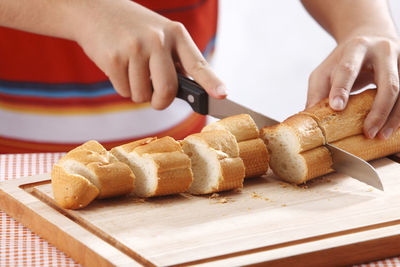 Midsection of man cutting loaf of bread on table