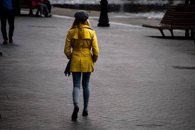 Full length rear view of woman walking on footpath