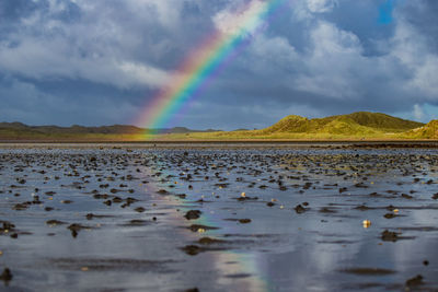 Scenic view of rainbow over lake against sky