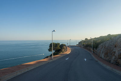 Road by sea against clear sky