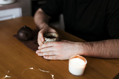 Young man holding a cup of tea in his hands in his kitchen