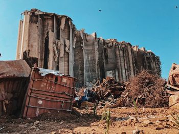 View of damaged rock formation on land against clear sky