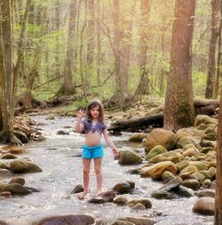 Full length of woman standing on rock in forest