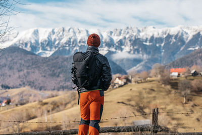 Rear view of man standing on snowcapped mountain