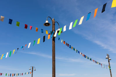 Low angle view of bunting flags hanging against blue sky