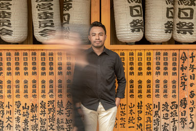 Portrait of young man standing against wall