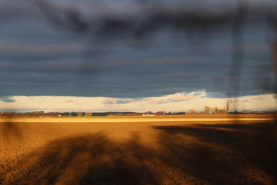 Scenic view of landscape against dramatic sky during sunset