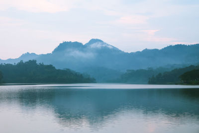 Scenic view of lake by mountains against sky