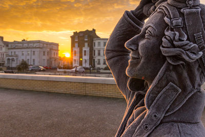 Close-up of statue against buildings during sunset