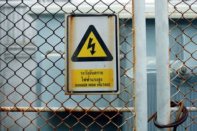 Close-up of warning sign on metal fence