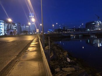 Illuminated buildings by river against sky in city at night