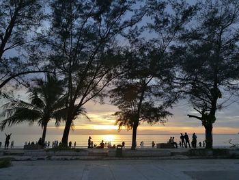 Silhouette people on beach against sky during sunset