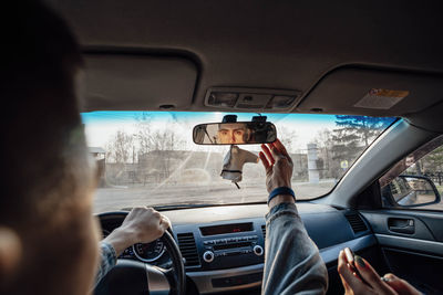 Young adventurer ensures safe journey by adjusting car's rearview mirror, covering topic of travel 