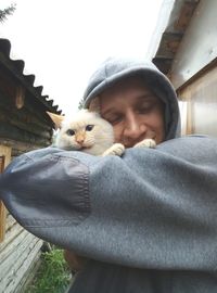 Close-up of man embracing cat in back yard