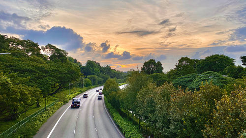 Road amidst trees against sky during sunset