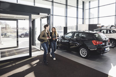 Friends talking while entering in car showroom