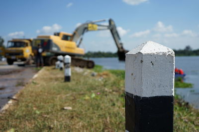 Close-up of machinery on field by road against sky