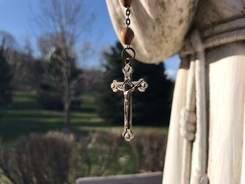 Cross chain hanging from statue 