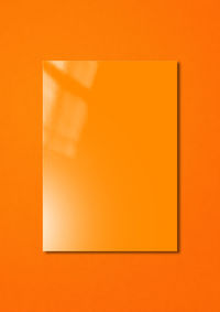 Low angle view of paper against orange wall