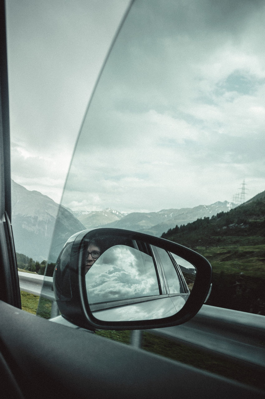 REFLECTION OF CAR ON SIDE-VIEW MIRROR AGAINST SKY