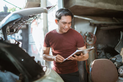 Portrait of young man using mobile phone while sitting in workshop