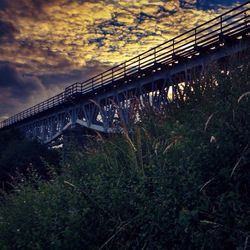 Bridge over river against cloudy sky