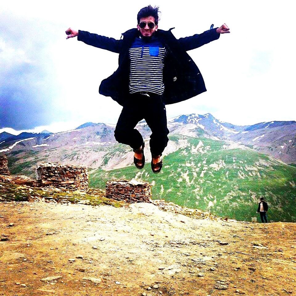 full length, lifestyles, leisure activity, mountain, casual clothing, landscape, sky, young adult, person, mountain range, standing, arms outstretched, front view, jumping, mid-air, young men, freedom, hiking