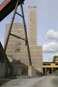 Low angle view of bridge amidst buildings against sky