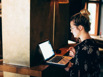 Woman using phone while sitting on table