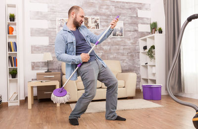 Full length of man holding camera at home